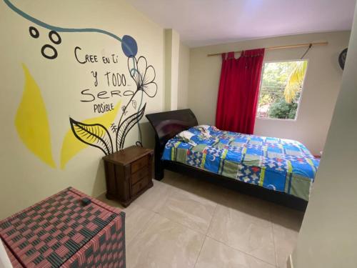 a bedroom with a bed and a sign on the wall at hostal los cascabeles de la sierra in Santa Marta