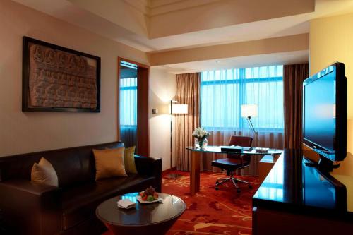 a living room with a couch and a tv and a table at Suzhou Marriott Hotel in Suzhou