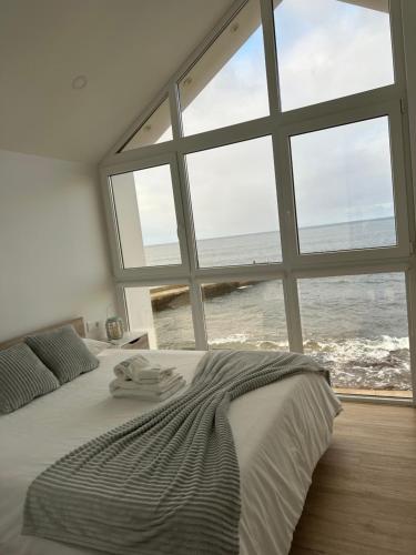 a bedroom with a large bed with a view of the ocean at Casa dos Anjos in Vila do Porto
