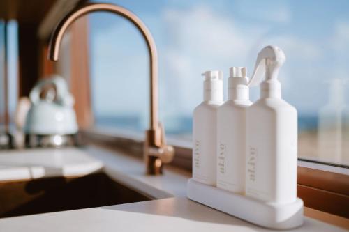 a counter with three bottles ofodorizers sitting next to a sink at EyreWay in Tulka