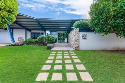 a garden with a brick pathway in front of a building at Lily Pad Retreat - A Luxe Poolside Parap Oasis in Paraparap