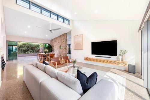 a living room with a large couch and a flat screen tv at Lily Pad Retreat - A Luxe Poolside Parap Oasis in Paraparap
