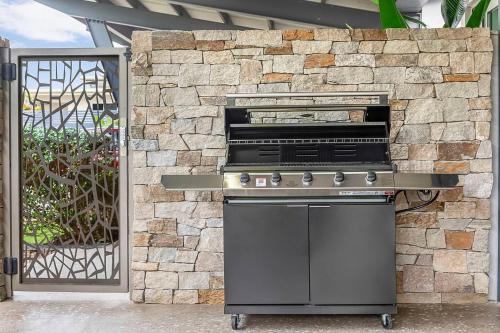 a stove in front of a stone wall at Lily Pad Retreat - A Luxe Poolside Parap Oasis in Paraparap