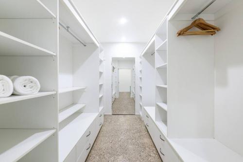 a white walk in closet with white shelves at Lily Pad Retreat - A Luxe Poolside Parap Oasis in Paraparap