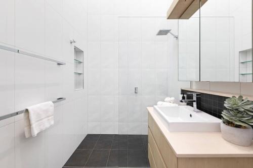 a white bathroom with a sink and a shower at Lily Pad Retreat - A Luxe Poolside Parap Oasis in Paraparap