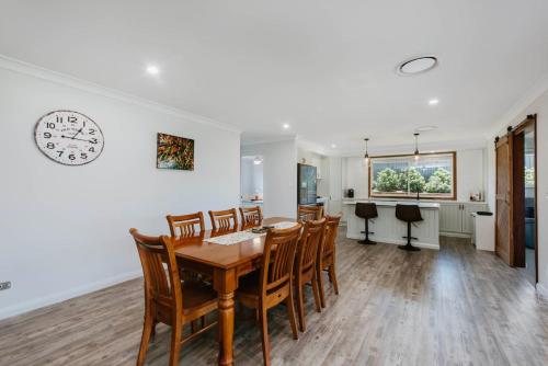 a dining room with a table and chairs and a clock on the wall at Kooyong - A Family Escape in Caerleon Estate in Mudgee