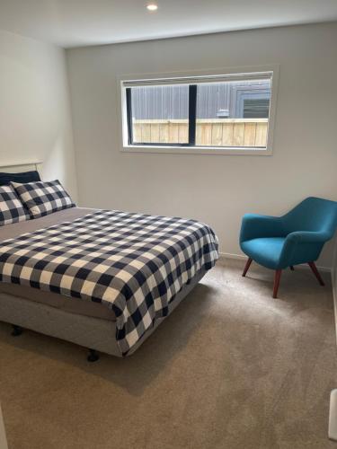 una camera da letto con un letto e una sedia blu di Remarkable stay 2 a Queenstown Airport