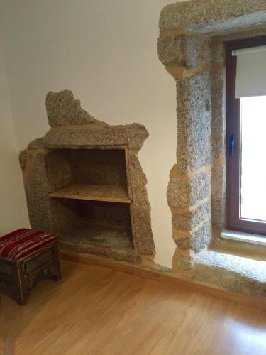 a stone fireplace in a room with a window at Moinhos do Pisão in Povoa Dao