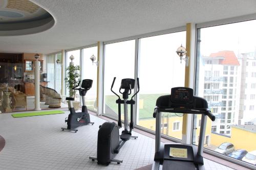 a gym with cardio machines in a room with windows at Hotel Strandperle in Cuxhaven