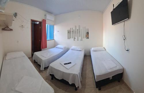 a hospital room with two beds and a television at Hotel Pousada Mãe Rainha in Trindade