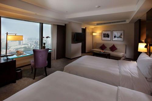 a hotel room with a large bed and a desk and a couch at Shangri-La Far Eastern Tainan in Tainan