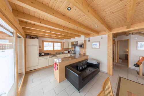 a kitchen and living room with a black leather couch at Chalet Nid Blanc in Nendaz