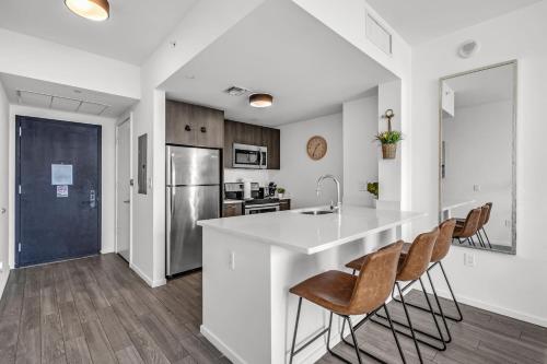 a kitchen with a large white counter and chairs at Experience Miami Modern 2 Bed Near Biscayne Blvd in Miami