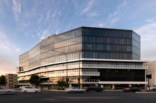 a large glass building with cars in front of it at Crowne Plaza Adelaide Mawson Lakes by IHG in Adelaide