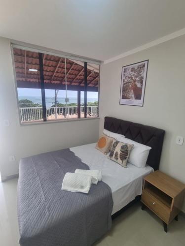 a bedroom with a bed with a table and a window at Jabuticaba Sabará - Frente ao Mar na Praia de Meaípe, Guarapari in Guarapari