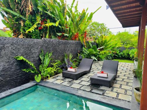 a patio with two chairs and a swimming pool at Uma Jala Villa Ubud in Ubud