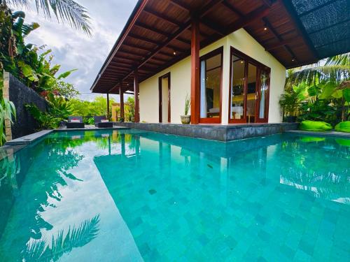 a swimming pool in front of a house at Uma Jala Villa Ubud in Ubud