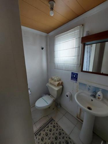 a bathroom with a toilet and a sink at Hostal de la Avenida in Punta Arenas