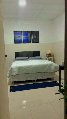 a bedroom with a bed with three pictures on the wall at Kitnet 17B in São Luís