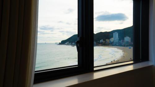 a view of a beach from a window at H avenue Songjeong in Busan