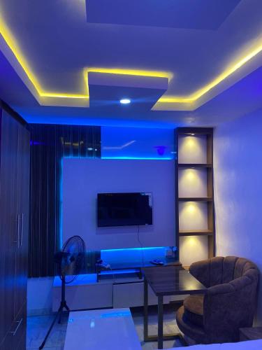 a living room with a tv and a couch and a table at Cee&Tee ABK 1BEDROOM -247Electricity - Solar Inverter AC in bedroom in Abeokuta