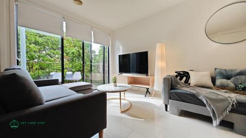 a living room with a couch and a tv at Modern 2-Bedroom Townhouse Near DFO & RMIT in Bundoora