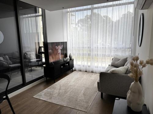 a living room with a couch and a large window at Brunswick Apartment with Car Park in Melbourne