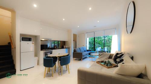 a living room and kitchen with a couch and a table at Modern 2-Bedroom Townhouse Near DFO & RMIT in Bundoora
