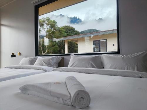 a bedroom with three white beds and a large window at The Pampines Villa, Mount Kinabalu in Ranau