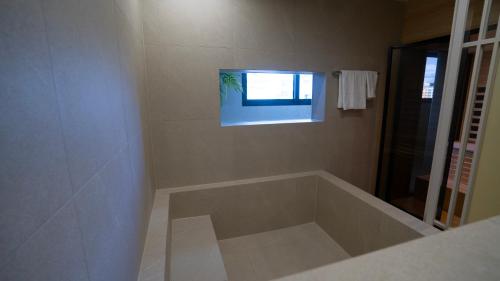 a bathroom with a large bath tub with a window at H avenue Songjeong in Busan