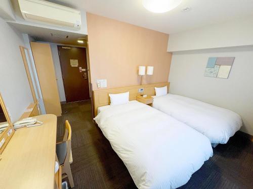 a hotel room with two beds and a desk at Hotel Route-Inn Sakata in Sakata
