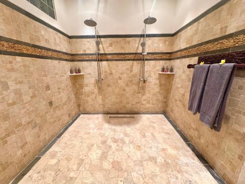 a tiled shower with two towels and two lights at Suara Jiwa Luxury Villas with Private Pool in Ubud