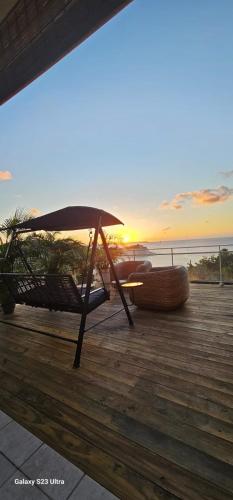 a chair and an umbrella on a deck with the sunset at Sunset View in Friar's Bay