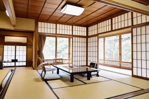 a room with a table and chairs in a room with windows at Kansuitei Kozeniya in Tottori