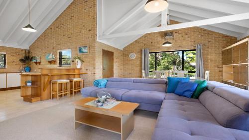 a living room with a blue couch and a table at Seahorse On Fawcett in Brunswick Heads