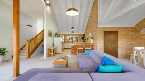 a living room with a blue couch and a brick wall at Seahorse On Fawcett in Brunswick Heads