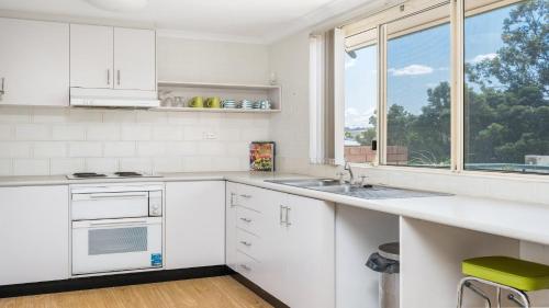 a white kitchen with a sink and a window at Top Of The Town in Brunswick Heads
