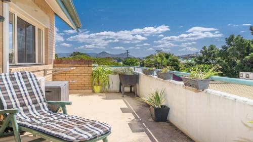 a patio with a chair and a balcony with plants at Top Of The Town in Brunswick Heads