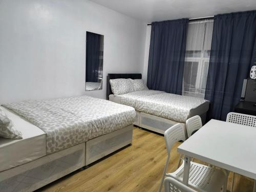a bedroom with two beds and a table and chairs at 4 person room 3min from South Wimbeldon tube station Room2 in London