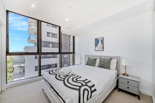 a bedroom with a large bed and a large window at Stylish 2BR Apt with Pool & Views Near Parramatta in Sydney