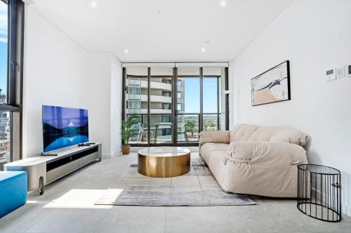a living room with a couch and a tv at Stylish 2BR Apt with Pool & Views Near Parramatta in Sydney