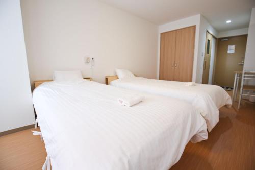 大阪市にあるConnect Innの白いシーツが敷かれた部屋にベッドが2つ