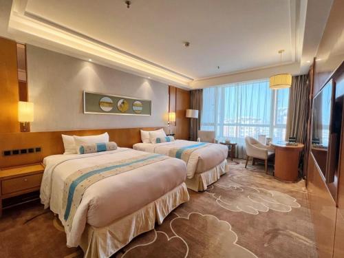 a hotel room with two beds and a desk at Menshine Gloria Plaza Hotel in Shantou