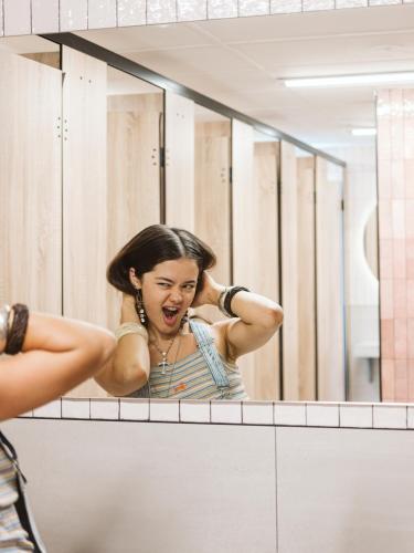 a woman brushing her hair in front of a mirror at Nate's Place Backpackers Sydney in Sydney
