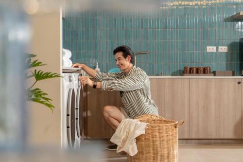 a man is sitting on a basket looking at a refrigerator at P-Park Hotel Pattaya in Pattaya North