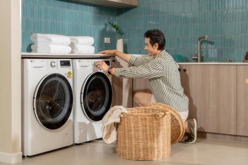 a man is loading a washing machine in a kitchen at P-Park Hotel Pattaya in Pattaya North