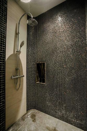 a shower in a bathroom with black tiles at Richmann Resort Hotel Hatyai in Hat Yai