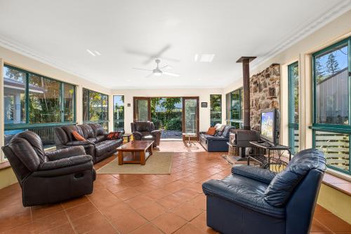 un soggiorno con mobili in pelle e finestre di Ronnies Cottage a Mylestom