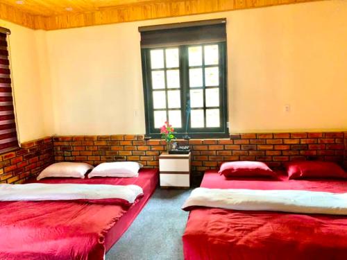 two beds in a room with a brick wall at Rosa Homestay in Ấp Trạm Hành