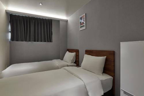 a small bedroom with two beds and a window at Eight Rest Hostel Jong-ro in Seoul